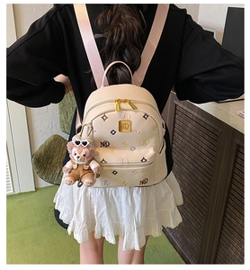 Detail of beige mini backpack with pink straps and a cute teddy bear plush charm