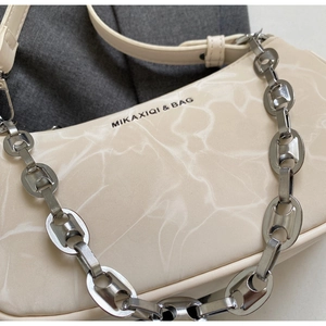Detailed macro view of the cream marble texture and silver chain strap on the shoulder bag