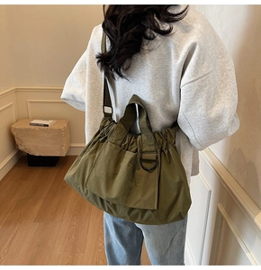 Detail of army green nylon tote bag featuring drawstring pleats and sturdy webbing straps