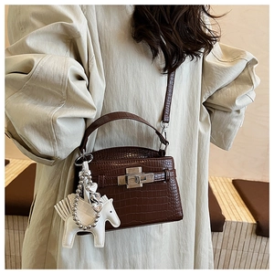 Detail of brown crocodile pattern handbag with silver clasp and white horse charm