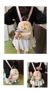 Detail of a white mini backpack with colorful monogram embroidery and a plush bear charm