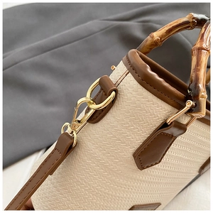 Detailed view of bamboo handle and woven texture on beige bucket bag with gold hardware