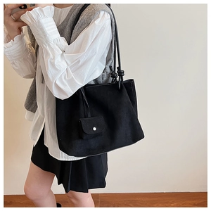 Detail of black suede tote bag with unique knot shoulder strap and small hanging pouch