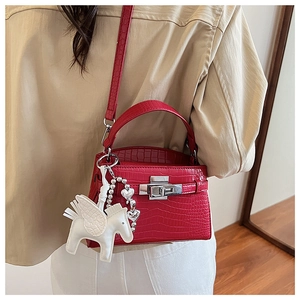 Detail of red crocodile texture handbag with silver lock and white pegasus charm accessory