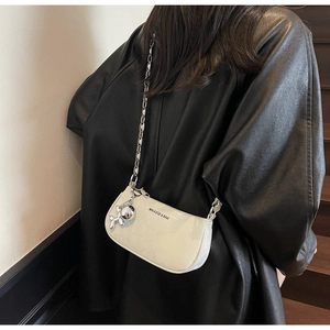 Detail of off-white glossy underarm bag with silver chain and balloon dog charm
