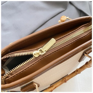 Detail of bamboo handle bucket bag with gold zipper and woven texture finish
