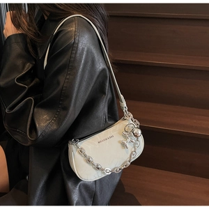 White shoulder bag with silver chain and balloon dog charm shown on a model