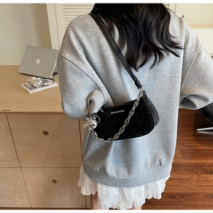 Close-up of black glossy leather underarm bag with silver chain and rabbit charm