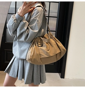 Detail of khaki nylon tote bag with drawstring texture and black metal D-ring buckle