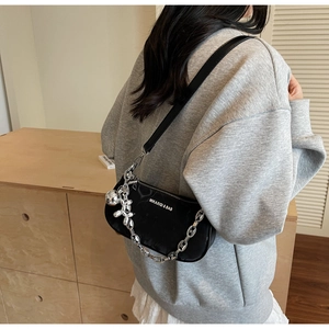 Detail of black underarm bag with silver chain and cute balloon dog charm on hoodie