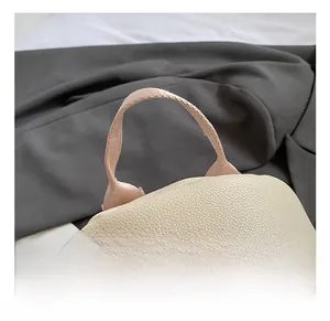 Close-up of the cream lychee grain leather backpack with dual metal zippers and fabric handle