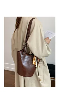 Detail of dark brown tote bag with crocodile pattern and colorful wooden bead charm