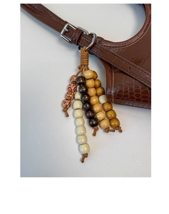 Close-up of retro wooden beaded charm with woven rope detail on brown textured tote bag