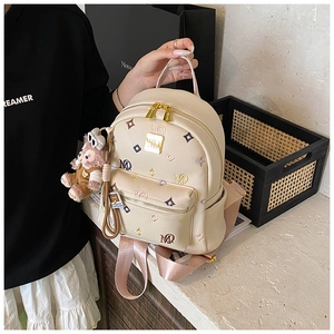 Close-up of beige faux leather backpack with colorful monogram and cute plush charm