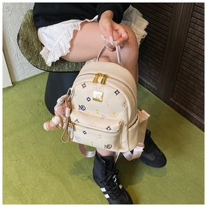 Detail of beige mini backpack featuring colorful MD lettering and pink teddy bear charm