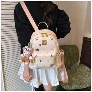 Detail of cream mini backpack featuring MQ embroidery and cute plush bear charm