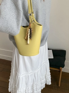 Yellow faux crocodile embossed tote bag with beaded charm accessory on model