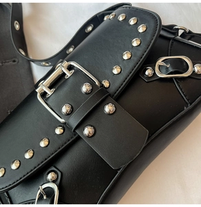 Detail der Silbernieten und Metallschnalle an der schwarzen Punk-Umhängetasche aus Leder