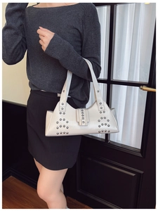 Detail of white leather tote with silver rivets and wide shoulder strap in Y2K style