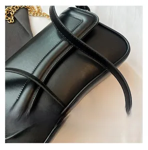 Gros plan du sac bandoulière en cuir noir montrant la texture et la chaîne dorée