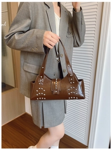 Detail of vintage brown leather tote bag with silver metal rivets and buckle accents