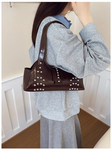 Detail of silver rivets on a dark brown glossy leather underarm bag for women