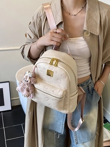 Creamy leather backpack with bear embossed pattern and pink straps on female model