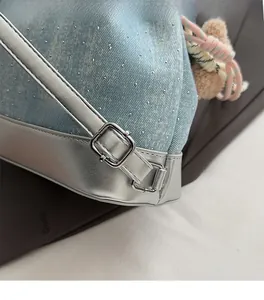 Détail du sac à dos en denim bleu clair avec strass étincelants et boucles argentées
