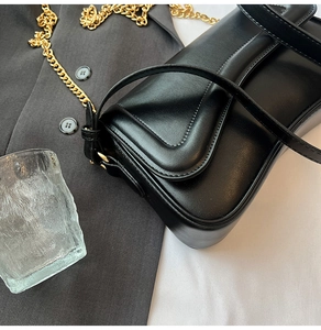 Vue détaillée d'un sac en cuir noir avec surpiqûres incurvées et chaîne en métal doré
