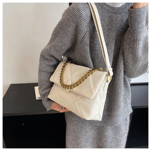 Detail van witte gewatteerde crossbodytas met gouden ketting en lederen textuurafwerking