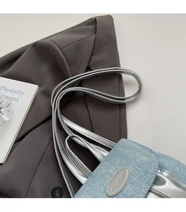 Détail du mini sac en denim bleu clair avec bandoulière en cuir argenté et logo