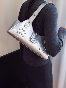Silver metallic tote bag with punk rivets and irregular design on a female model