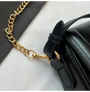 Détail du sac en cuir noir avec bandoulière chaîne dorée et coutures précises