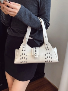 Chic cream tote bag with silver studs and polished faux leather in a model photoshoot