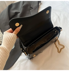 Vue détaillée du compartiment intérieur zippé et de la chaîne dorée du sac en cuir