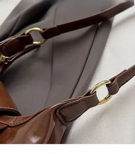 Close-up of premium gold-tone circular hardware and dark brown glossy leather handbag