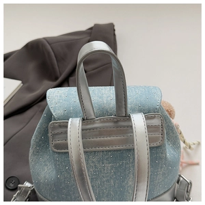 Détail d'un sac à dos en denim bleu avec clous argentés et breloque en fourrure rose