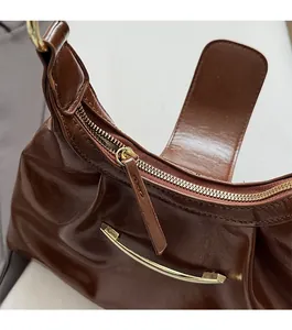 Close-up of smooth gold zipper and polished dark brown leather on vintage dumpling bag