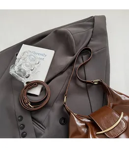 Close-up of vintage brown leather handbag with gold metal clasp on gray suit background