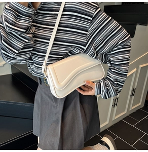 Détail du sac sous le bras en cuir blanc cassé avec rabat incurvé et boucle en métal doré