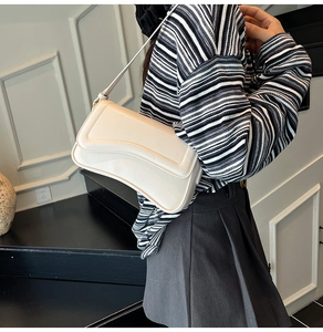 Détail du sac sous l'aisselle crème montrant le cuir lisse et le rabat incurvé