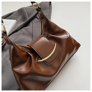 Detail of dark brown vintage dumpling bag showing glossy pleated leather and gold buckle