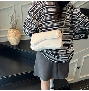 Vue détaillée du sac à bandoulière beige avec rabat ondulé et bandoulière en chaîne dorée