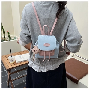Gros plan d'un mini sac à dos bleu clair et rose avec porte-clé ours et rabat magnétique