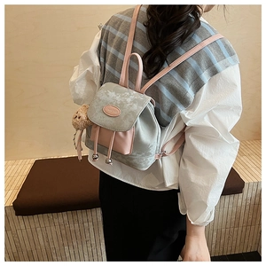 Détail d'un mini sac à dos effet marbre avec un pendentif ours en peluche sur un mannequin