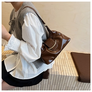 Detail of vintage dark brown faux leather shoulder bag with gold metal buckle closure
