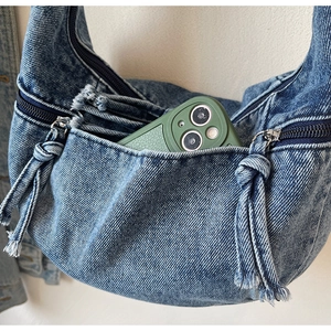 Détail du sac hobo en denim délavé avec poche zippée et tirette en cordelette tressée