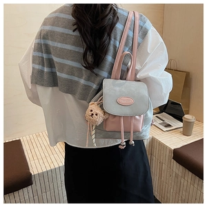 Détail du sac à dos gris bleu et rose avec breloque ours dans un cadre urbain chic