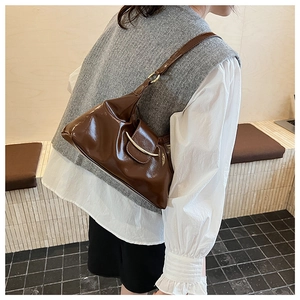 Close-up of brown glossy shoulder bag with golden metal buckle decoration on the strap