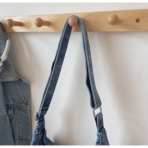 Détail du sac hobo en denim bleu montrant la texture délavée et la boucle métallique